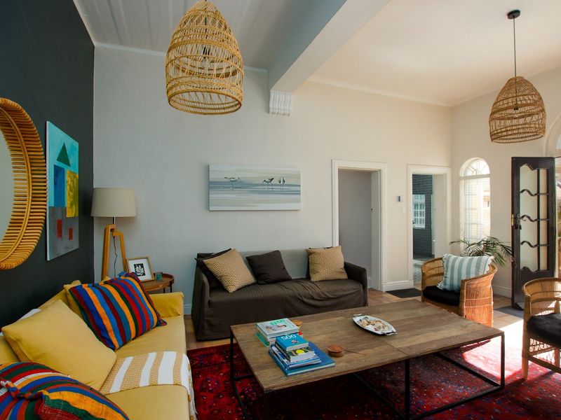 A bright living room featuring high ceilings with exposed beams, arched windows, and a glass panel door leading to an outdoor area.