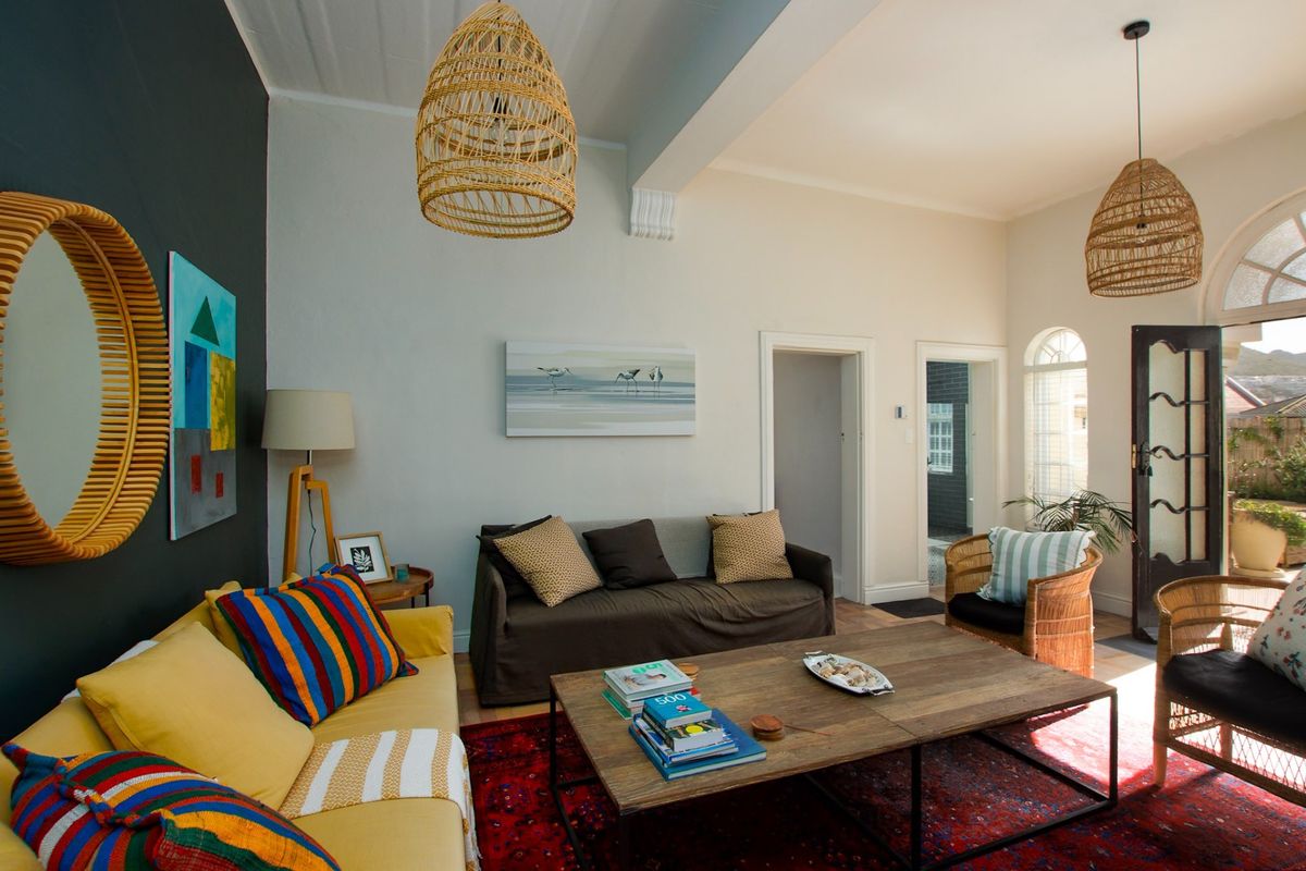 A bright living room featuring high ceilings with exposed beams, arched windows, and a glass panel door leading to an outdoor area.