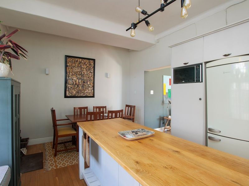 Open plan kitchen and dining area featuring a central island with a wooden countertop, built-in microwave, and modern pendant lighting.