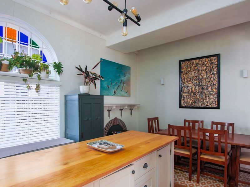 Open-plan living and dining area featuring a kitchen island, built-in fireplace, and a distinctive arched stained glass window with patterned floor tiles.