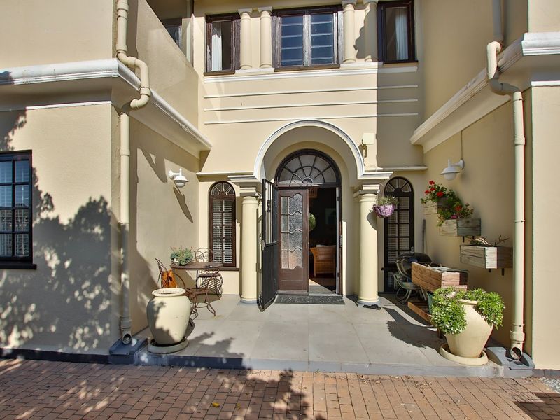 A well-maintained front entrance featuring an arched timber door, decorative columns, and stone paving, providing a welcoming and classic architectural aesthetic.