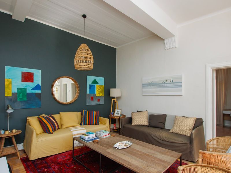 A well-maintained living room featuring exposed ceiling beams, timber flooring, and a striking dark accent wall.