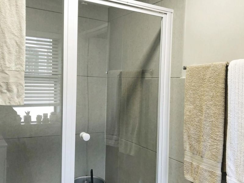 A clean bathroom featuring a glass-enclosed shower with neutral wall tiling and a functional towel rail.