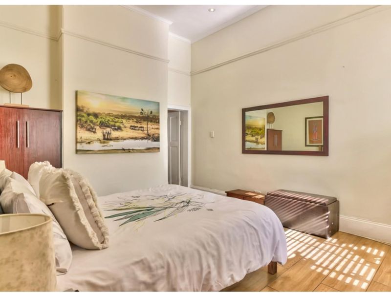 A well-maintained bedroom featuring timber flooring, classic picture rails, and recessed downlighting, offering a bright and comfortable living space.