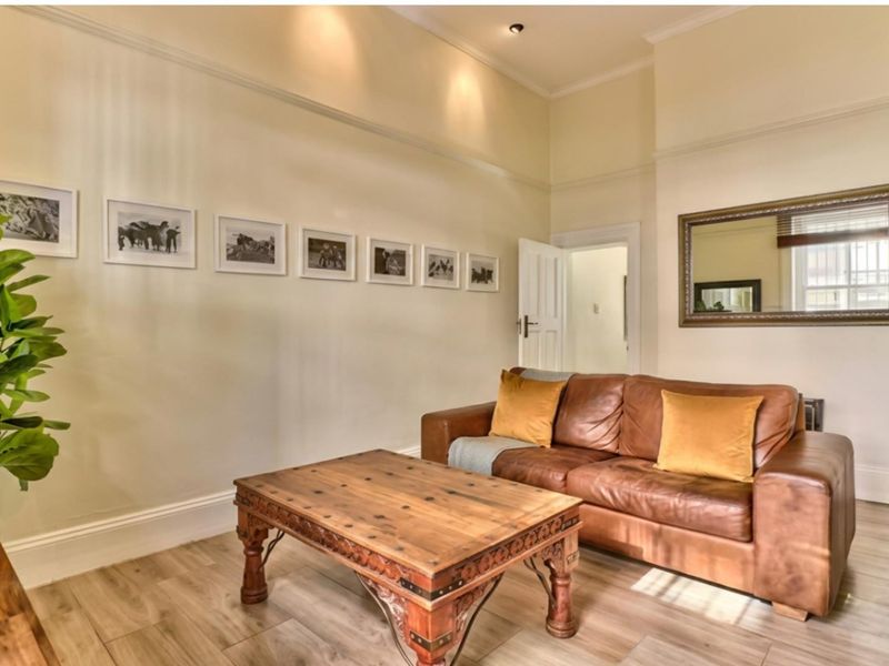 A well-maintained living room featuring laminate flooring, recessed downlights, and classic coving, creating a bright and inviting atmosphere.