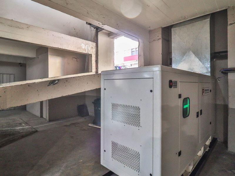 Utility area featuring a large industrial generator, exposed concrete structural elements, and ventilation ducting, suitable for commercial infrastructure requirements.