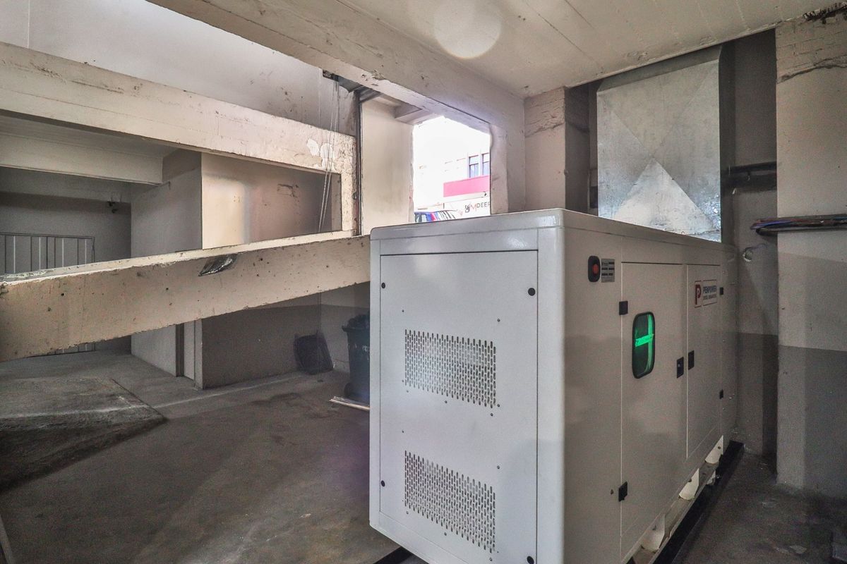 Utility area featuring a large industrial generator, exposed concrete structural elements, and ventilation ducting, suitable for commercial infrastructure requirements.