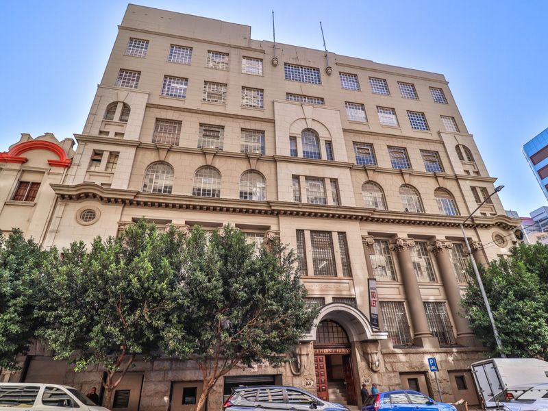 A grand, multi-story commercial building featuring a classical stone facade, arched entrance, and prominent architectural detailing in an urban setting.