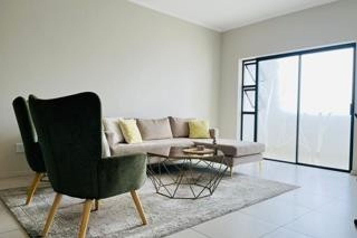 A bright and modern living room featuring neutral walls, tiled flooring, and a large sliding glass door providing access to the outdoors.