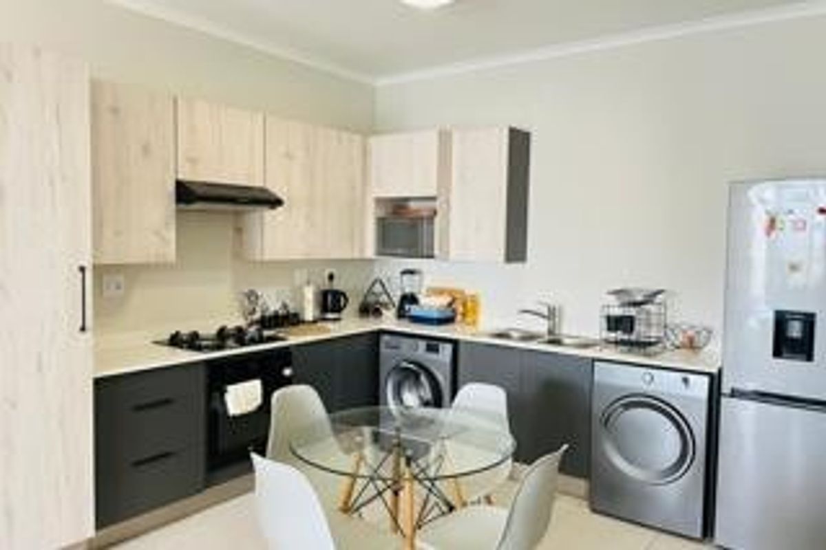 Modern kitchen featuring light wood and dark grey cabinetry, gas hob, built-in oven, microwave, and integrated laundry appliances.