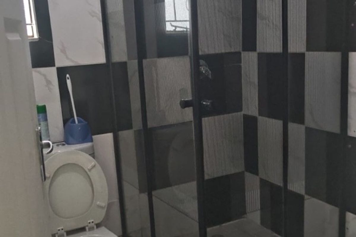 A modern bathroom featuring a corner shower enclosure with black framing and a high-contrast black and white tiled wall design.