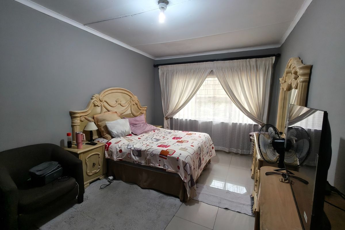 A bedroom featuring tiled flooring and a ceiling with visible cracking, providing a functional space ready for cosmetic updates.