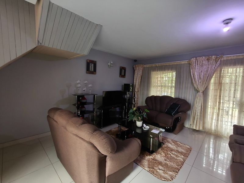 A living room featuring tiled flooring and a staircase bulkhead, providing a functional space for relaxation and entertainment.