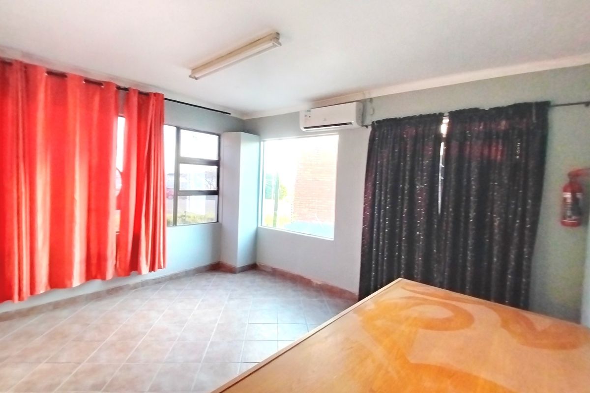 A bedroom featuring tiled flooring, an installed air conditioning unit, and large windows with curtains.