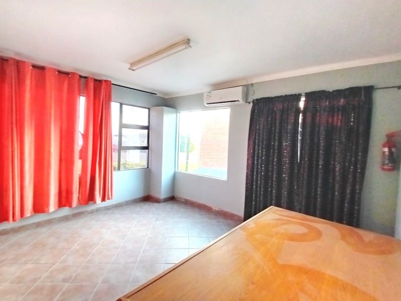 A bedroom featuring tiled flooring, an installed air conditioning unit, and large windows with curtains.