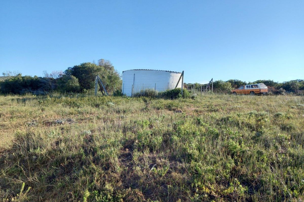 A view of a vacant residential plot featuring a white water tank and perimeter fencing set within natural vegetation.