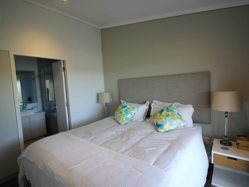A well-maintained bedroom featuring a neutral color palette, built-in headboard, and direct access to an en-suite bathroom.