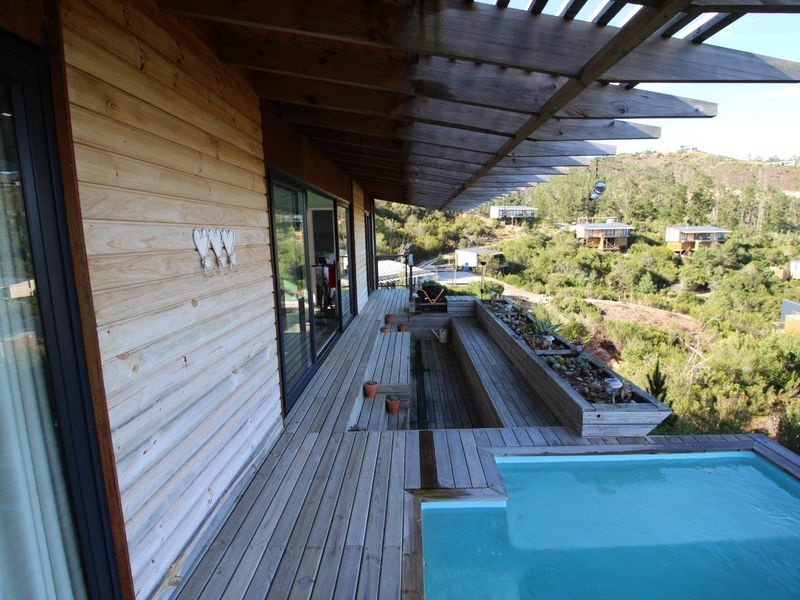 Elevated timber deck featuring a built-in plunge pool, timber pergola, and integrated planter boxes, offering scenic views of the surrounding landscape.
