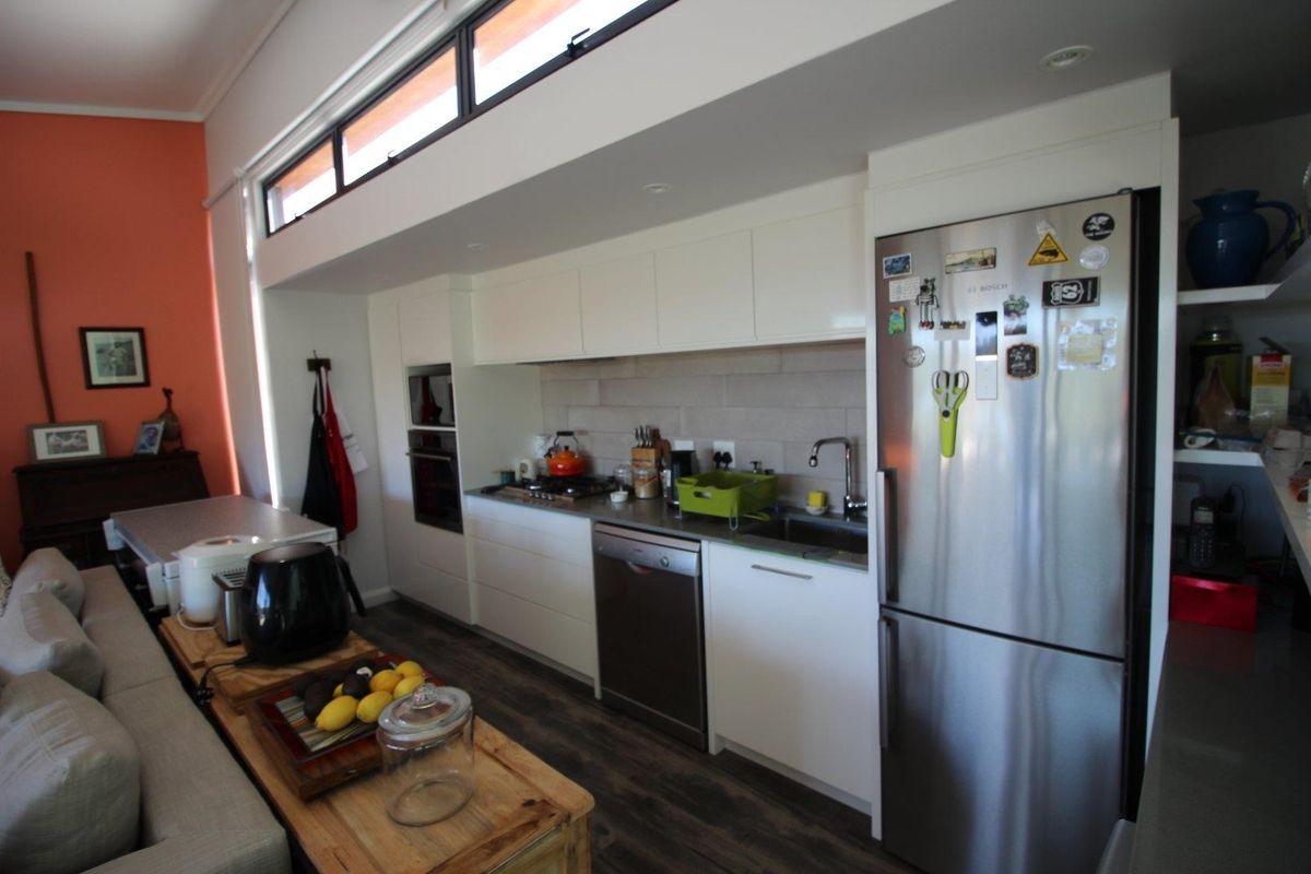 Modern kitchen featuring sleek white cabinetry, integrated appliances, a gas cooktop, and high-level clerestory windows providing natural light.