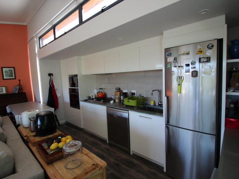 Modern kitchen featuring sleek white cabinetry, integrated appliances, a gas cooktop, and high-level clerestory windows providing natural light.