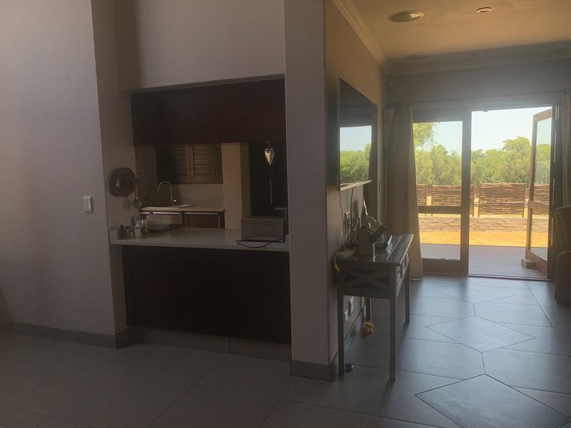 Open plan living area featuring a compact kitchen nook with built-in cabinetry and direct access to an outdoor patio through sliding glass doors.