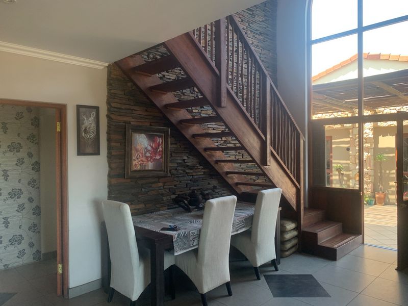 Living area featuring a striking stone-clad feature wall, a wooden staircase, and a large arched window providing natural light and access to the patio.