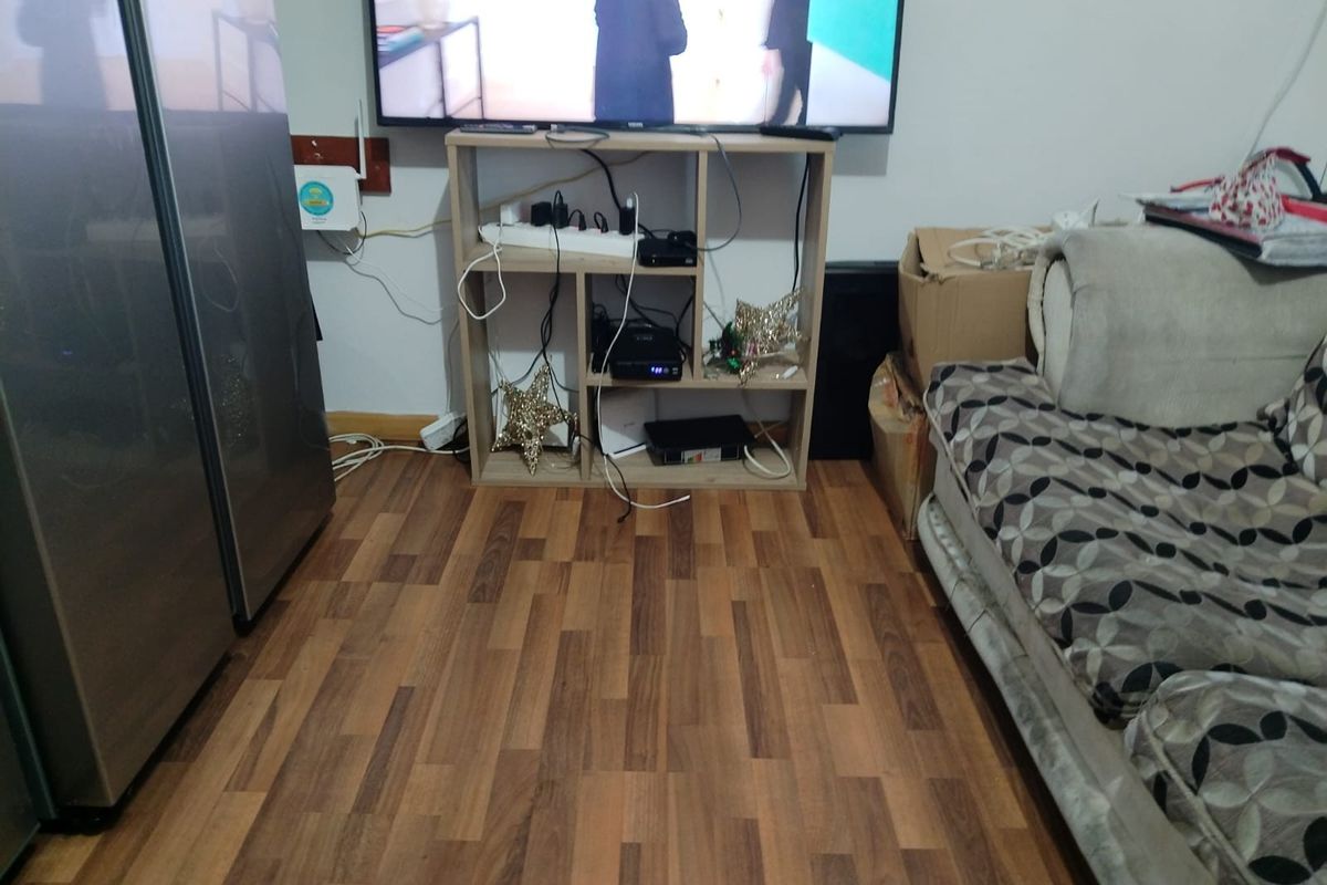 A living room area featuring wood-look laminate flooring and neutral wall finishes, providing a functional space for entertainment and relaxation.
