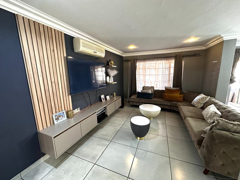 A modern living room featuring a slatted timber feature wall, built-in cabinetry, tiled flooring, and a wall-mounted air conditioning unit.