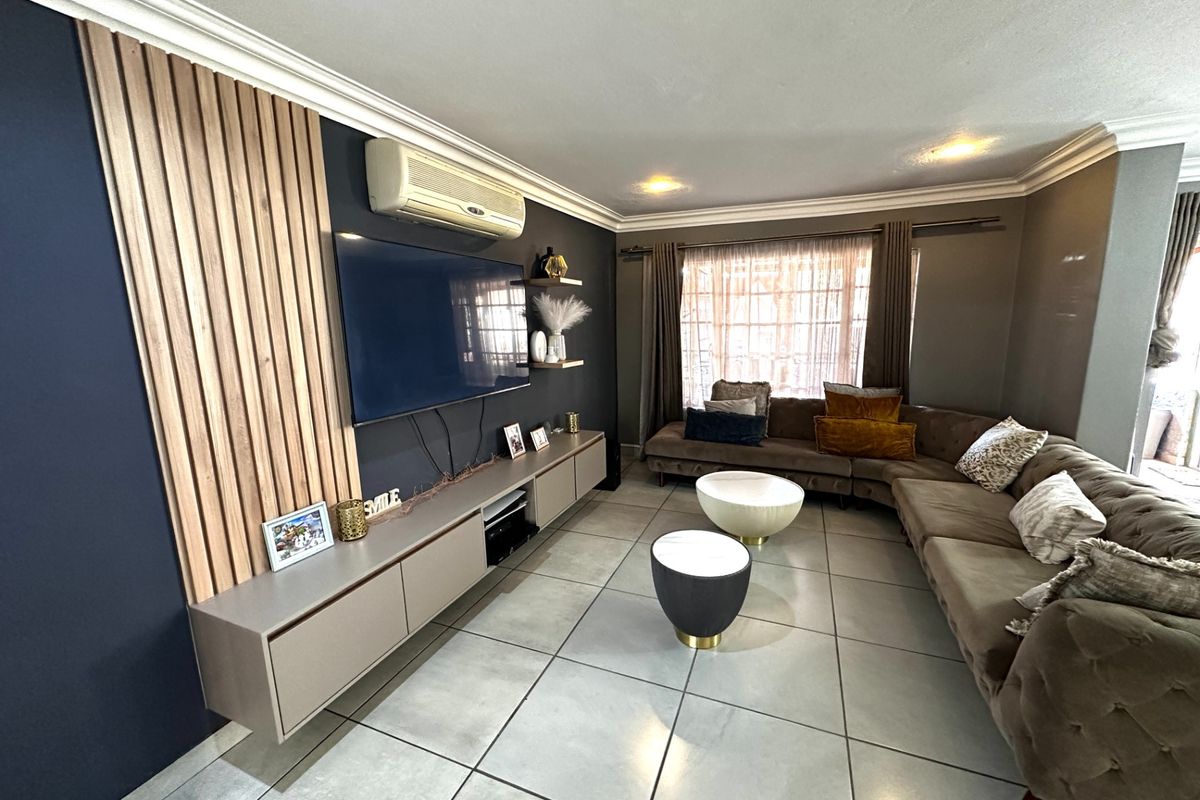 A modern living room featuring a slatted timber feature wall, built-in cabinetry, tiled flooring, and a wall-mounted air conditioning unit.