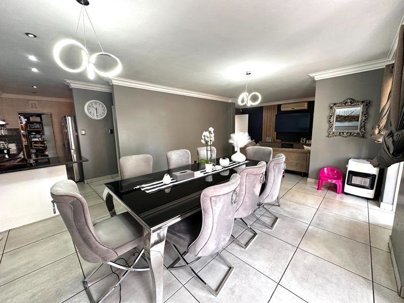 Spacious open-plan dining and living area featuring modern tiled flooring, contemporary pendant lighting, and crown molding throughout the space.