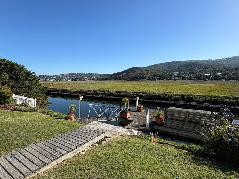 Scenic waterfront view featuring a private wooden jetty and walkway overlooking the river, marshlands, and distant hills.
