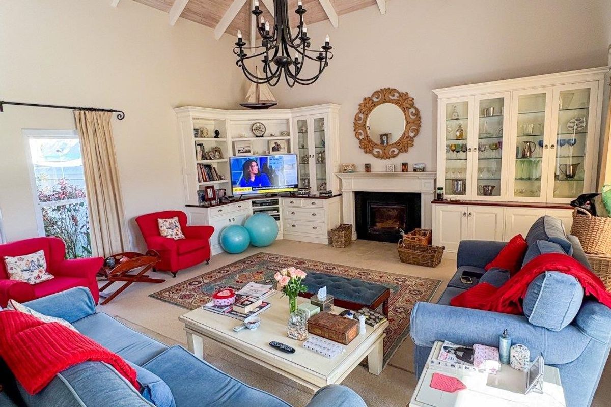 Spacious living room featuring a high vaulted timber ceiling, built-in cabinetry, and a central fireplace with a decorative mantelpiece.