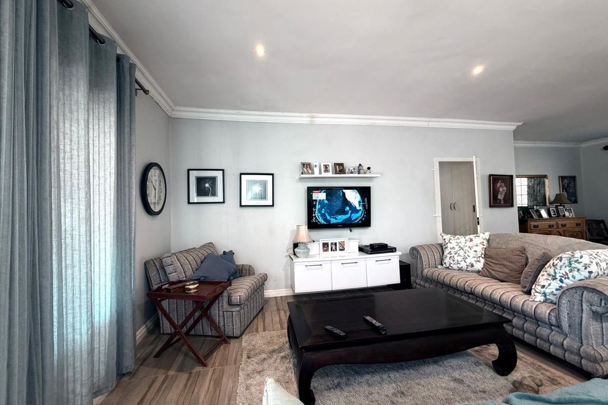 A comfortable living room featuring tiled flooring, crown molding, and recessed downlighting, creating a bright and inviting space for relaxation.