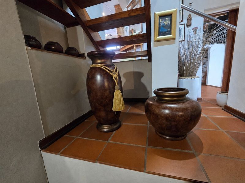 A hallway area featuring a wooden staircase, terracotta floor tiles, and a built-in wall niche for display.