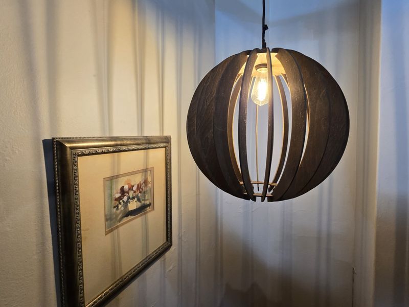 A close-up view of a decorative wooden pendant light fixture hanging in a corner.