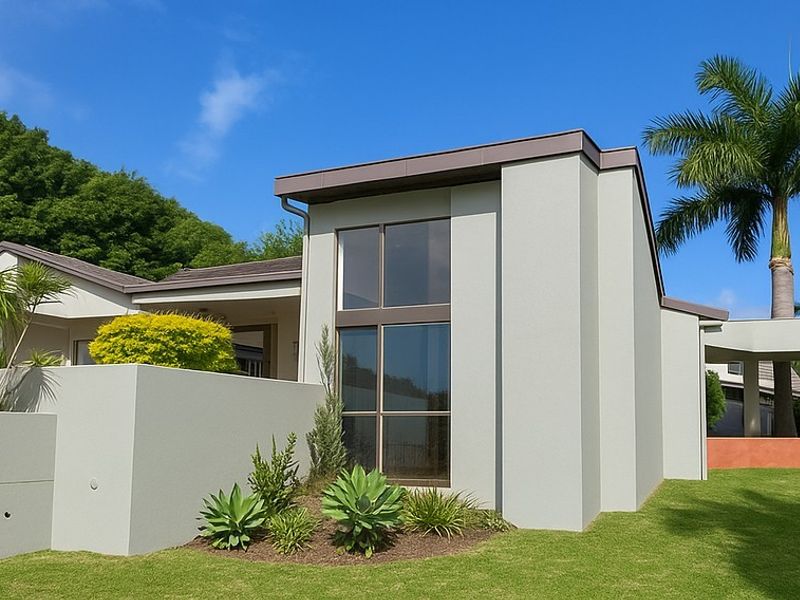 Modern architectural exterior featuring clean rendered lines, large windows, and a well-maintained landscaped garden with a covered walkway.