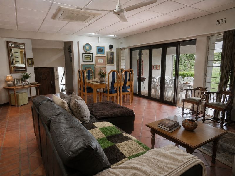 Spacious open-plan living and dining area featuring terracotta floor tiles, ceiling fan, and large sliding glass doors providing access to the outdoor patio.