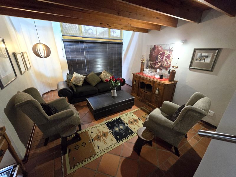A cozy living room featuring exposed timber ceiling beams and traditional terracotta floor tiles, creating a warm and inviting atmosphere.