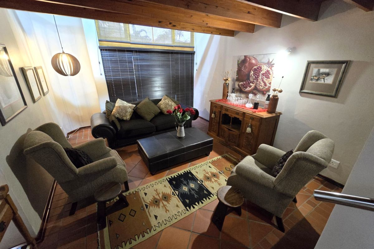 A cozy living room featuring exposed timber ceiling beams and traditional terracotta floor tiles, creating a warm and inviting atmosphere.