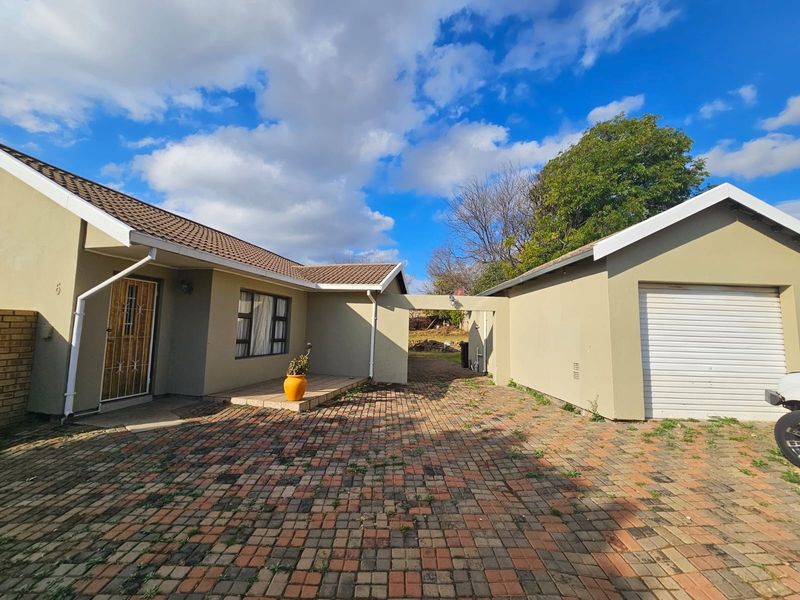 Front exterior view of the house featuring a brick paved driveway, a single garage with a roller door, and a covered entrance area.