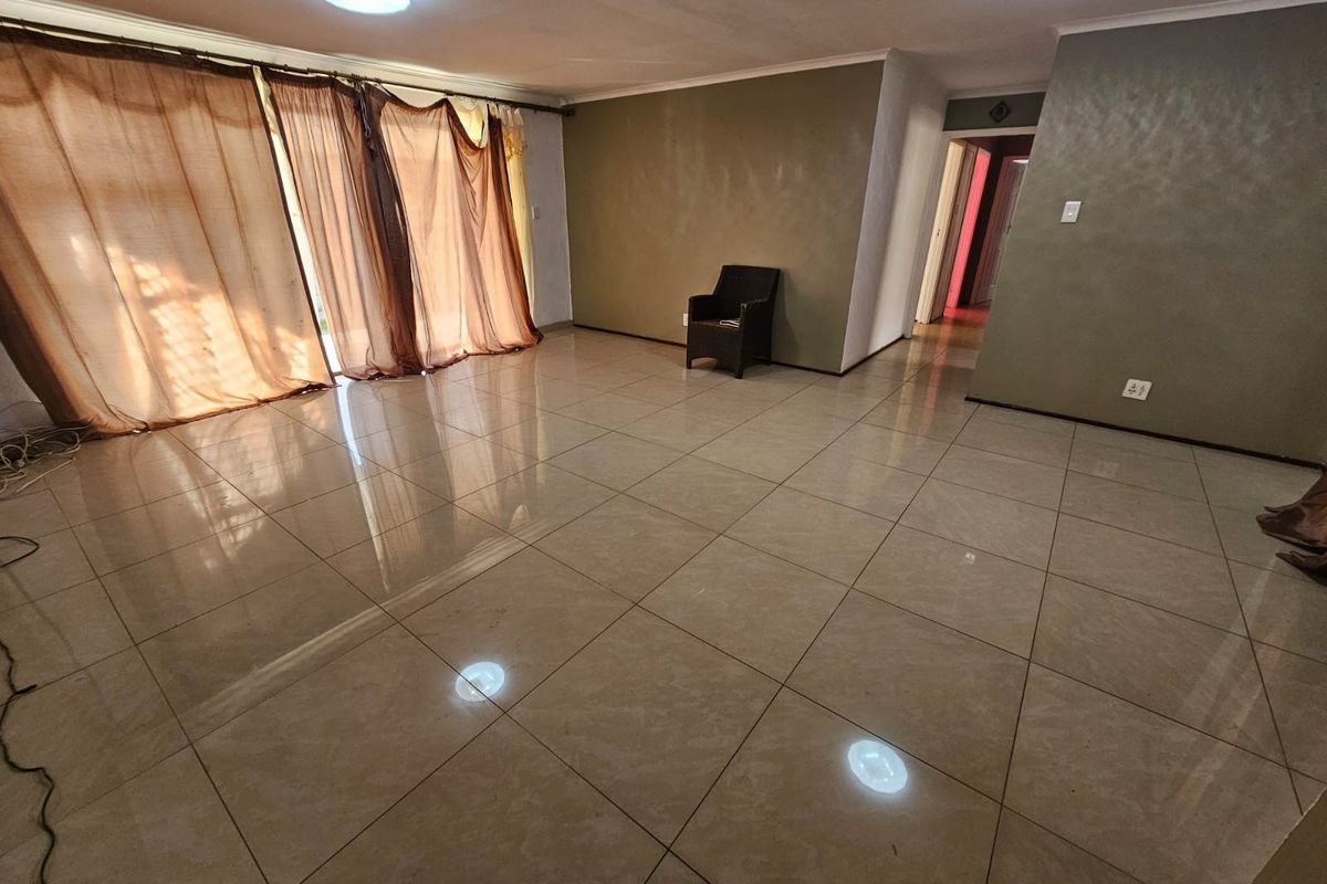 Spacious living area featuring large format floor tiles, sliding glass doors providing natural light, and recessed ceiling lighting.