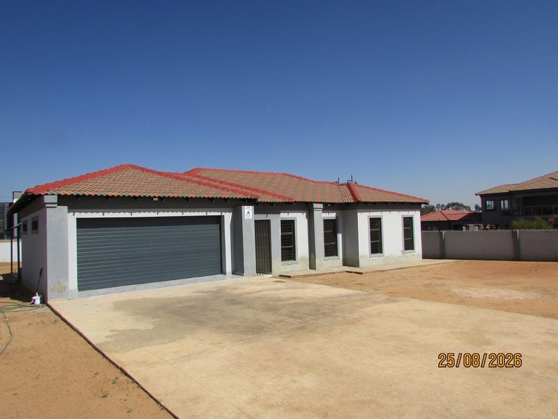 Front view of a single-story house featuring a tiled roof, automated garage, and concrete driveway, set within an unfinished garden area.