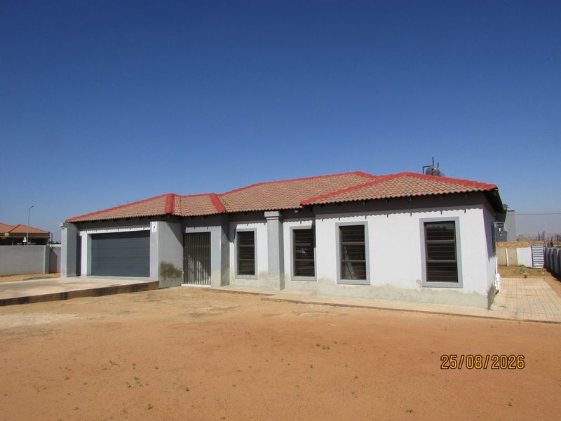 Front elevation of a single-story house featuring a tiled roof, integrated garage, and aluminium window frames, set on an undeveloped plot.