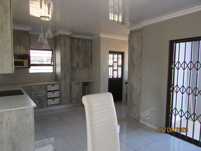 Modern kitchen featuring stone countertops, built-in cabinetry, and tiled flooring, with direct access to an exterior area through a security gate.
