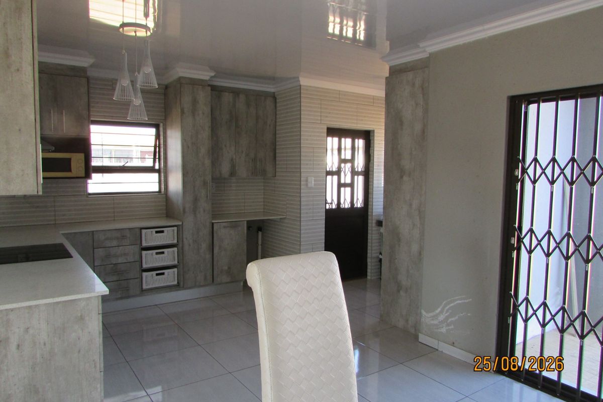 Modern kitchen featuring stone countertops, built-in cabinetry, and tiled flooring, with direct access to an exterior area through a security gate.