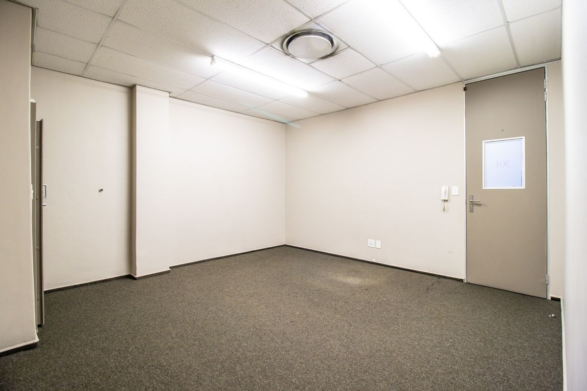 A vacant commercial office space featuring neutral walls, carpeted flooring, and a suspended ceiling with integrated lighting.