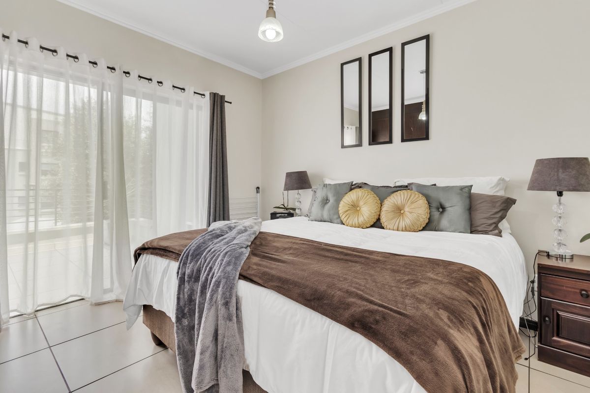 A well-maintained bedroom featuring neutral wall tones, tiled flooring, and a large sliding glass door providing access to an outdoor area.