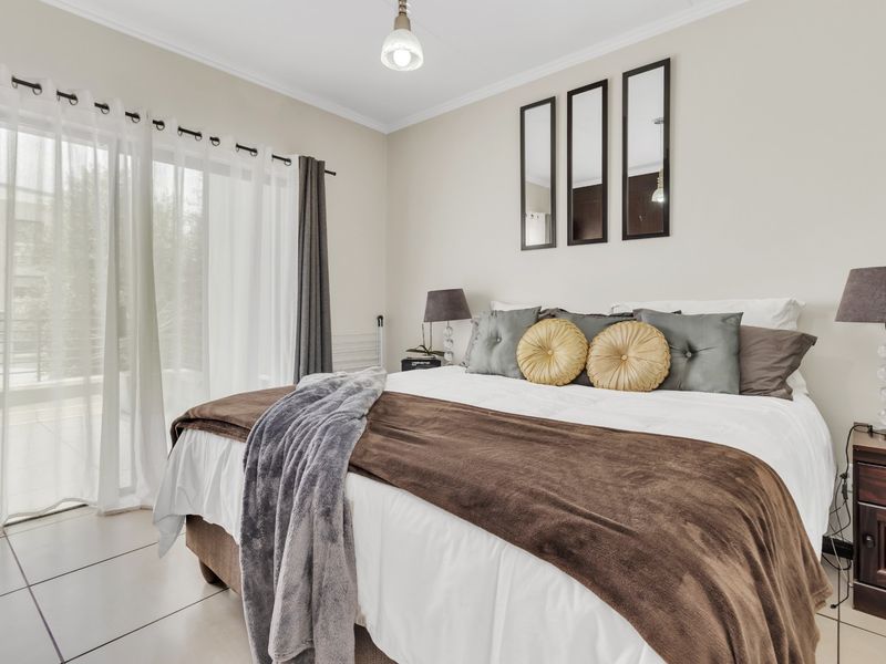 A well-maintained bedroom featuring neutral wall tones, tiled flooring, and a large sliding glass door providing access to an outdoor area.