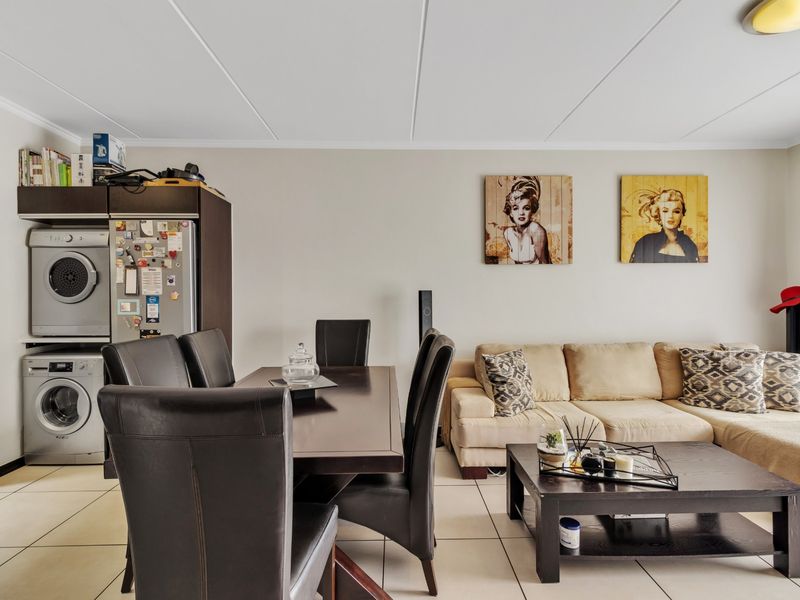 Open-plan living and dining area featuring tiled flooring and integrated laundry cabinetry, creating a functional and versatile space.