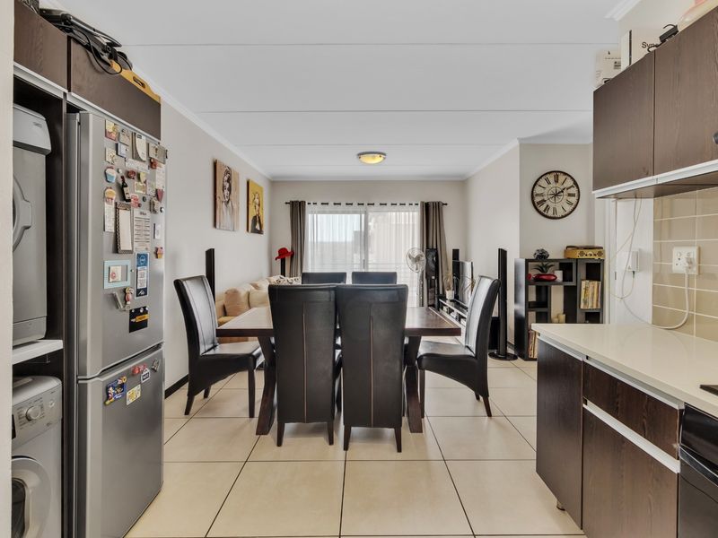 Open-plan living and dining area featuring tiled floors, modern dark cabinetry, and a sliding door leading to the exterior.